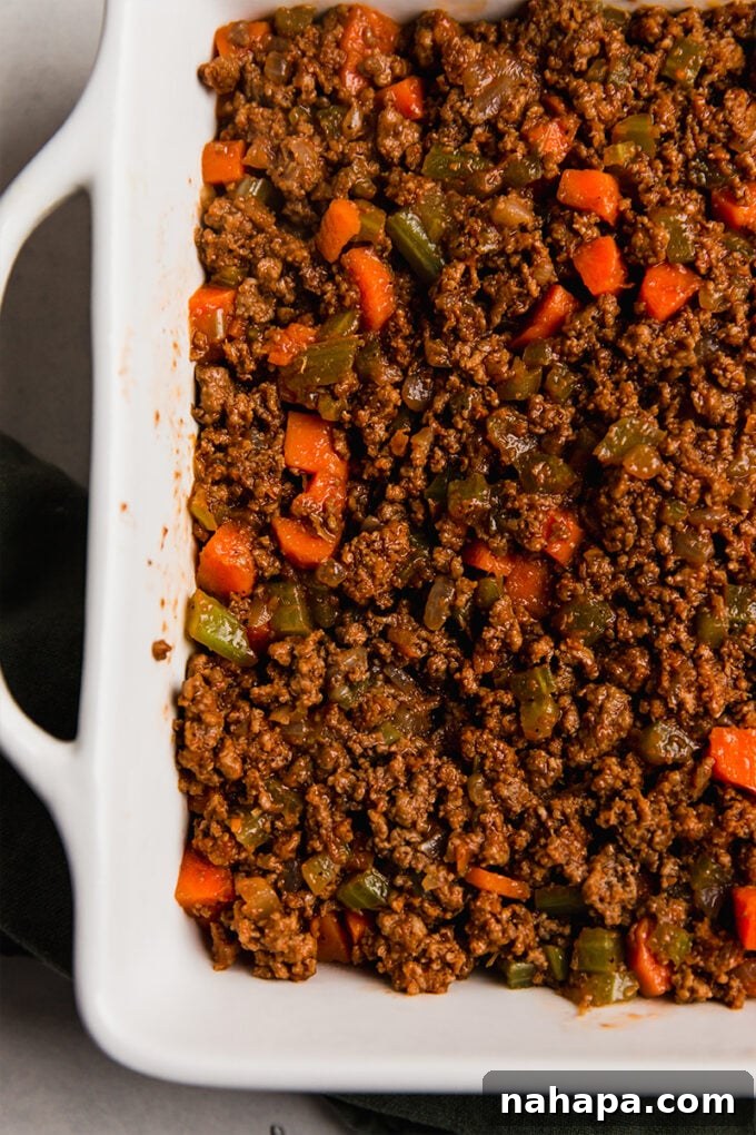 The base of sweet potato shepherd's pie with the beef and vegetable filling in a baking dish.