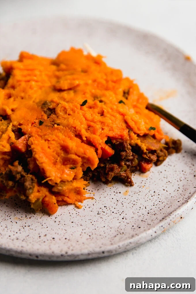 A serving of sweet potato shepherd's pie on a plate, garnished with fresh parsley.
