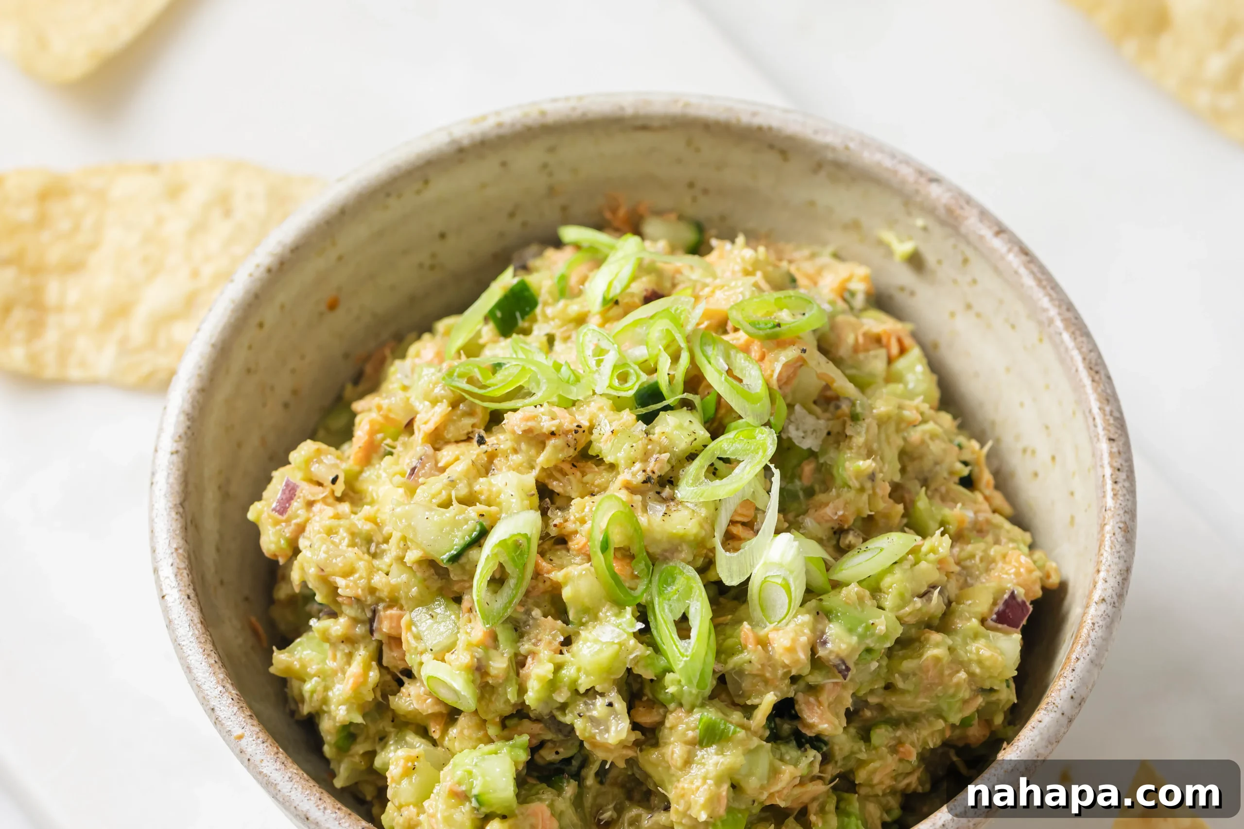 The finished avocado salmon salad, garnished with green onions, ready to be served.