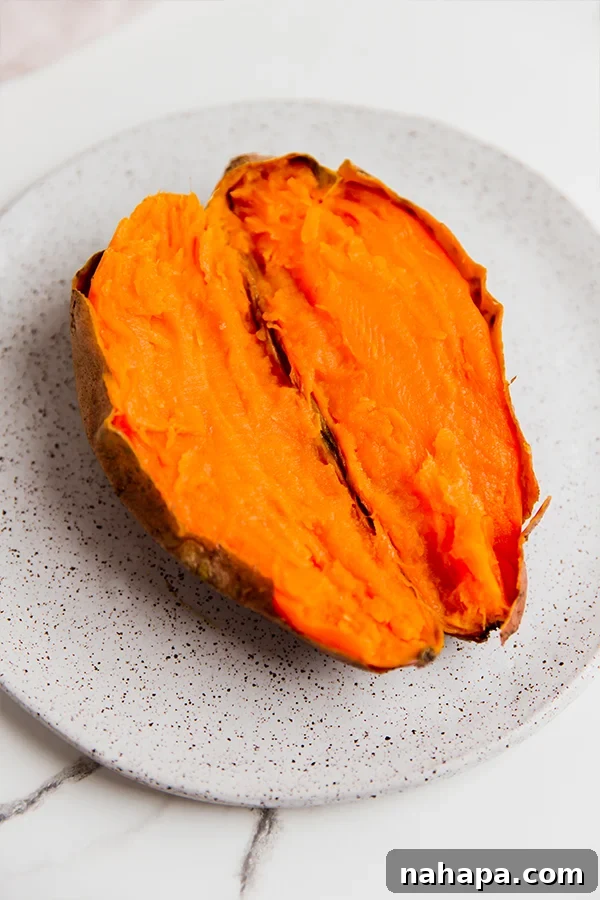 A sweet potato cut in half and open on a plate.