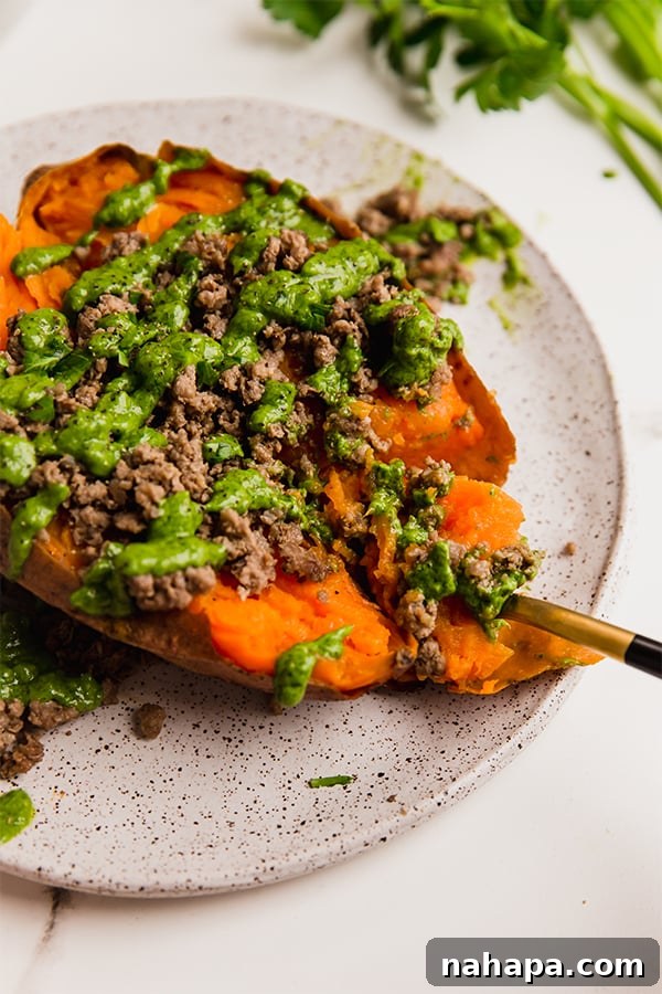 A ground stuffed sweet potato with avocado chimichurri on a plate.