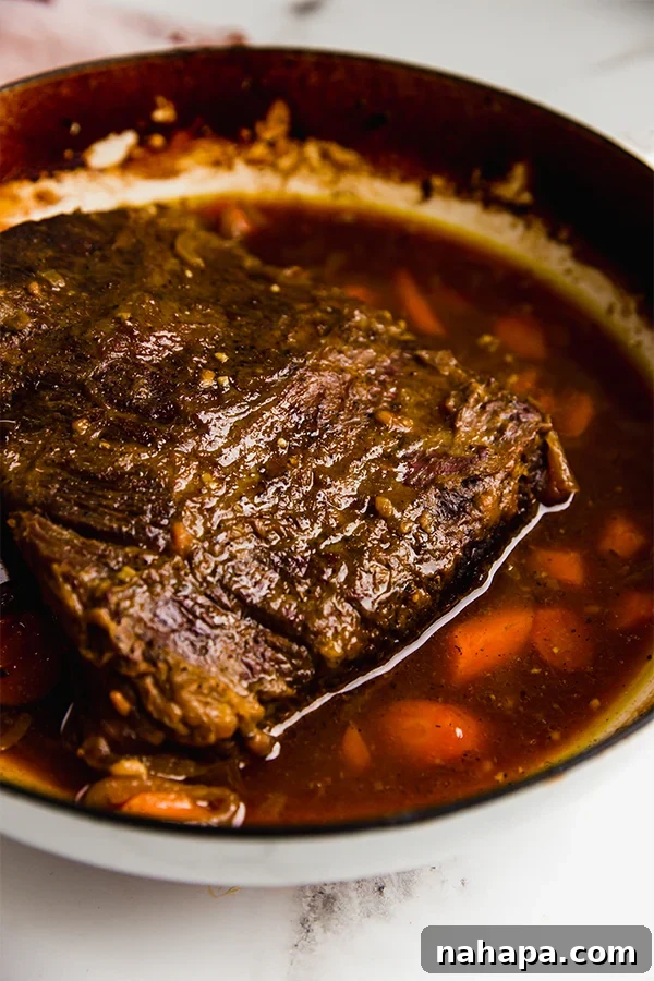 A large brisket, surrounded by aromatic vegetables, braising in a cast-iron Dutch oven, filling the kitchen with its savory aroma.