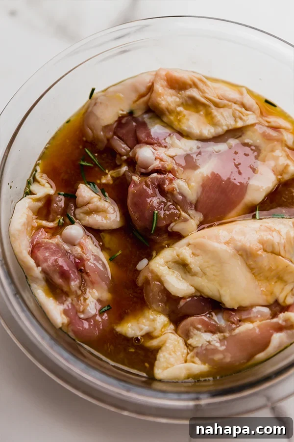 Chicken marinating in a glass bowl.