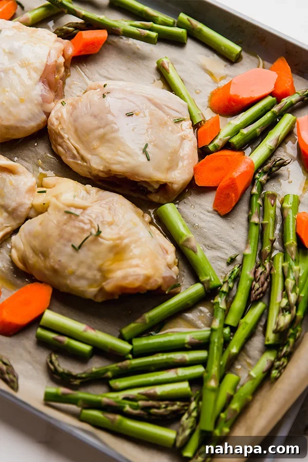 Chicken and vegetables arranged on a sheet pan ready for baking.