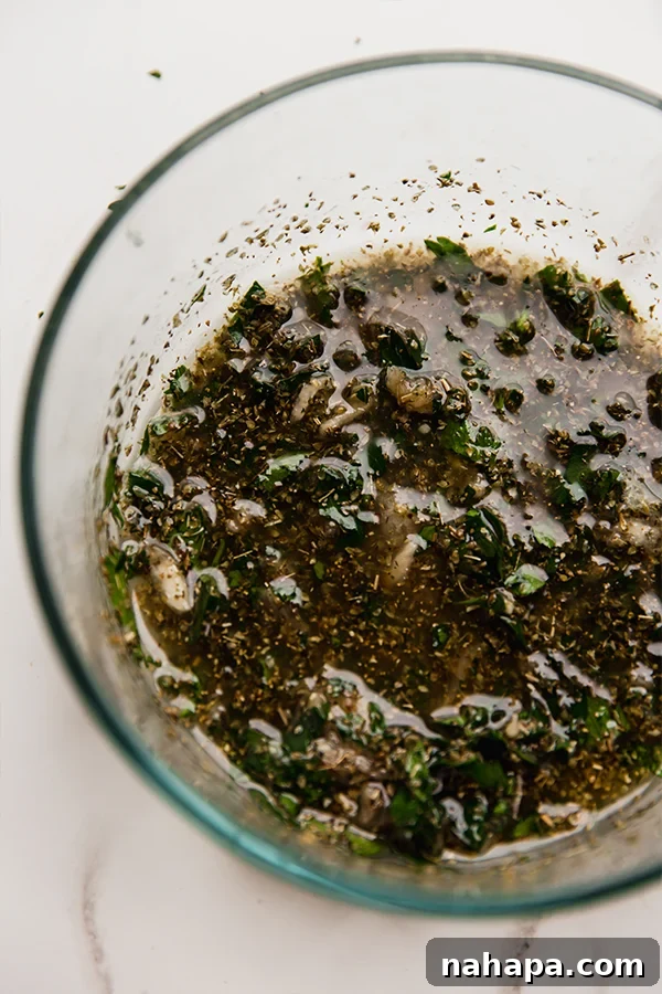 A bowl containing the rich, dark marinade for Chicken Marbella before the chicken is added.