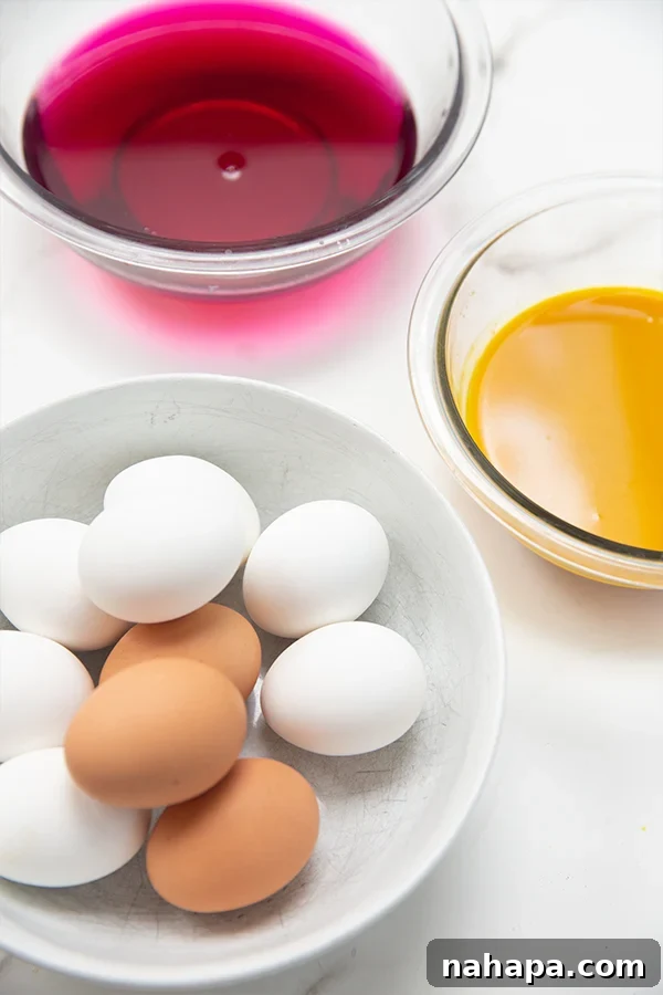 Various natural Easter egg dyes in glasses with hard-boiled eggs ready for immersion.