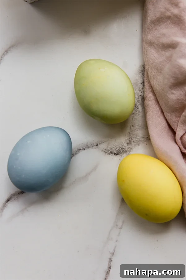 A collection of naturally dyed Easter eggs in blue, yellow, and green, beautifully displayed.