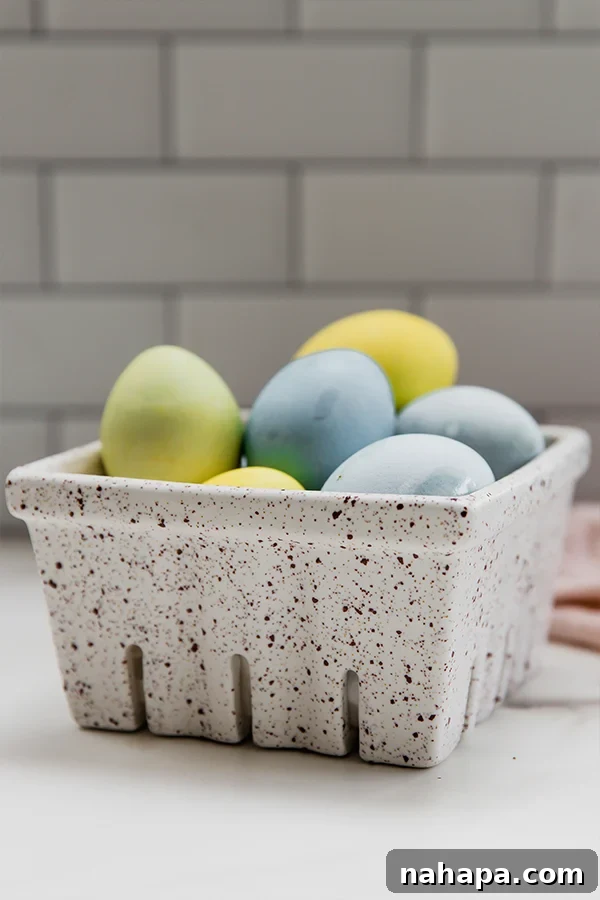 A charming close-up of naturally dyed Easter eggs resting gently in a rustic carton, highlighting their soft, organic colors.