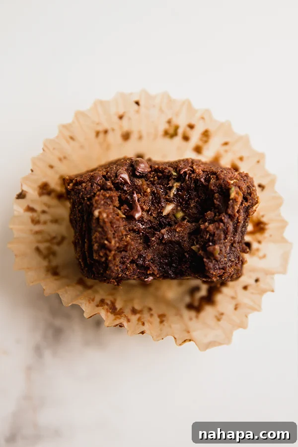 One perfectly baked chocolate zucchini muffin, showing its moist and tender interior.