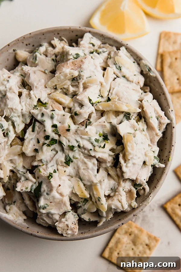 A bowl of tarragon chicken salad, garnished with fresh tarragon leaves, ready to be served.