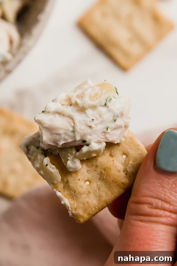 A cracker topped with a generous spoonful of tarragon chicken salad, ready to eat.