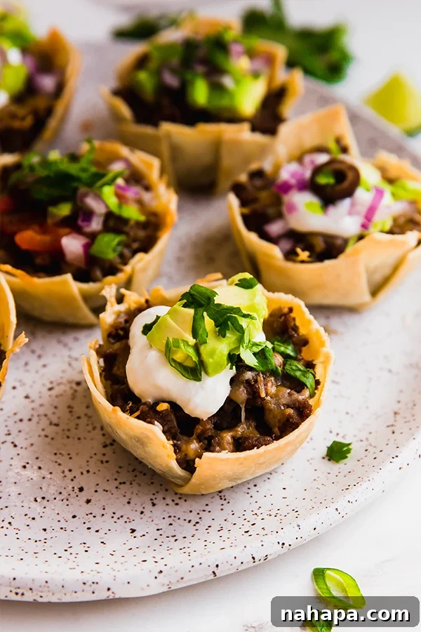 A plate with beautifully arranged mini taco cups, topped and ready to eat.