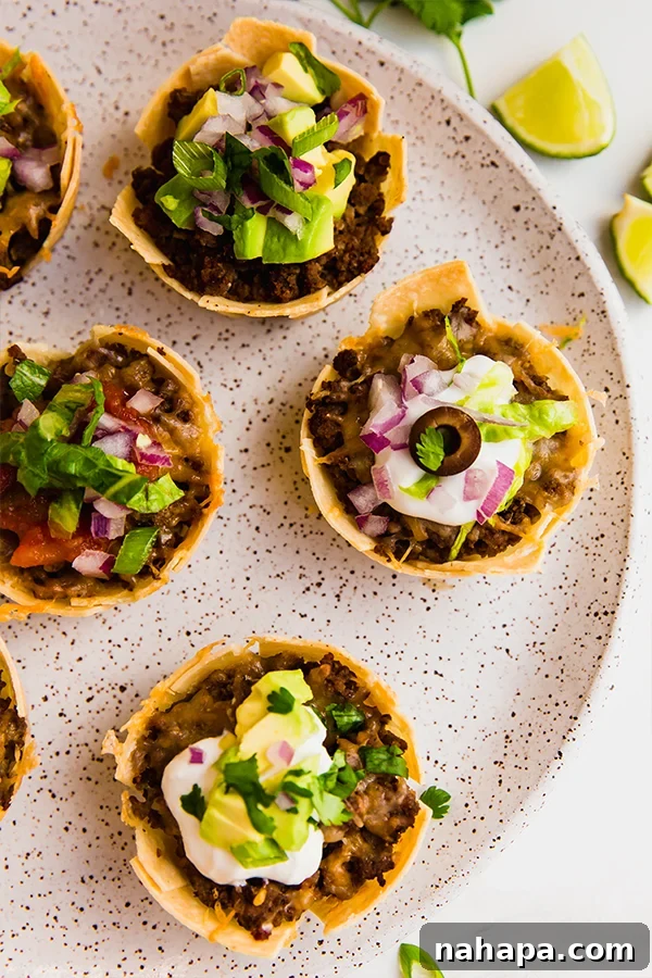 A vibrant plate filled with several mini taco cups, showcasing a variety of toppings and their appealing presentation.