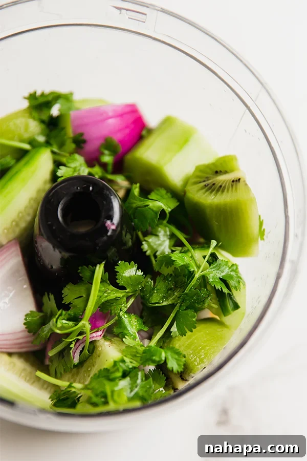 The vibrant ingredients for AIP nightshade-free salsa verde loaded into a food processor, ready to be blended.
