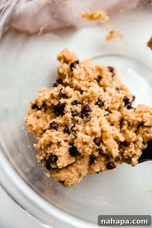 A bowl filled with raw chocolate chip cookie dough, ready to be formed and baked.
