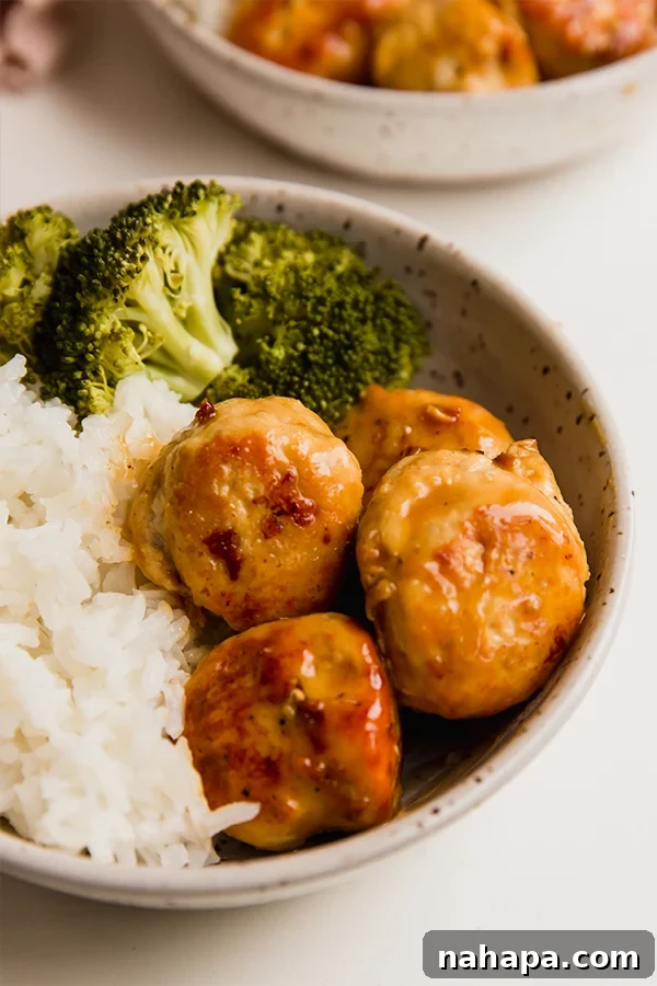 A bowl with orange chicken meatballs, rice, and broccoli, showcasing a healthy and vibrant meal.