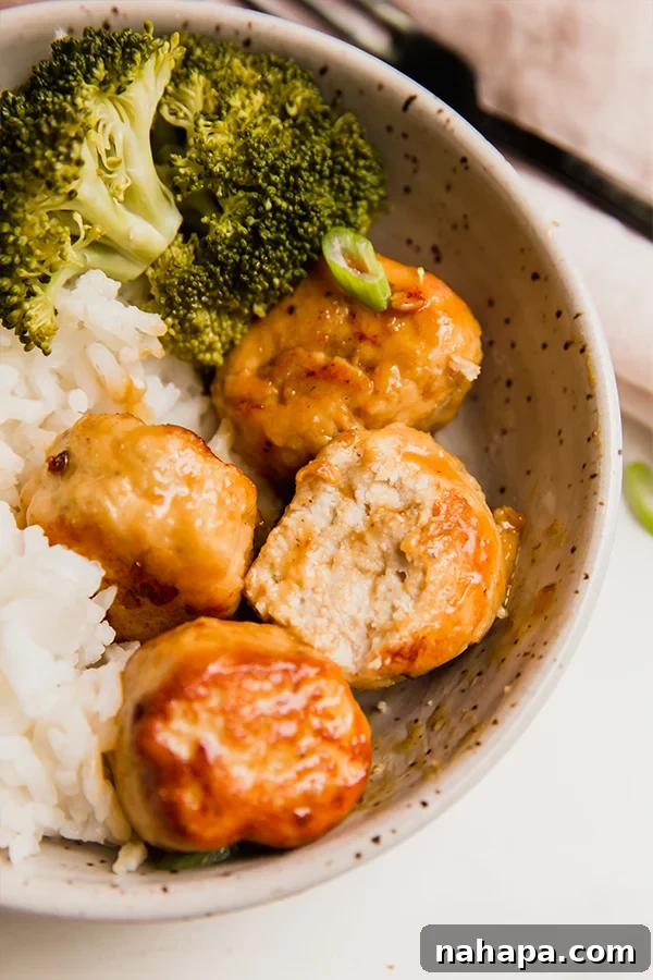A healthy bowl featuring orange chicken meatballs, fluffy rice, and vibrant green broccoli florets, ready to eat.