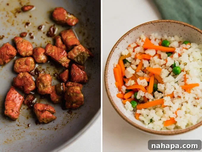 A pan with cooking salmon cubes next to a bowl of chopped vegetables including carrots, peas, and cauliflower rice.