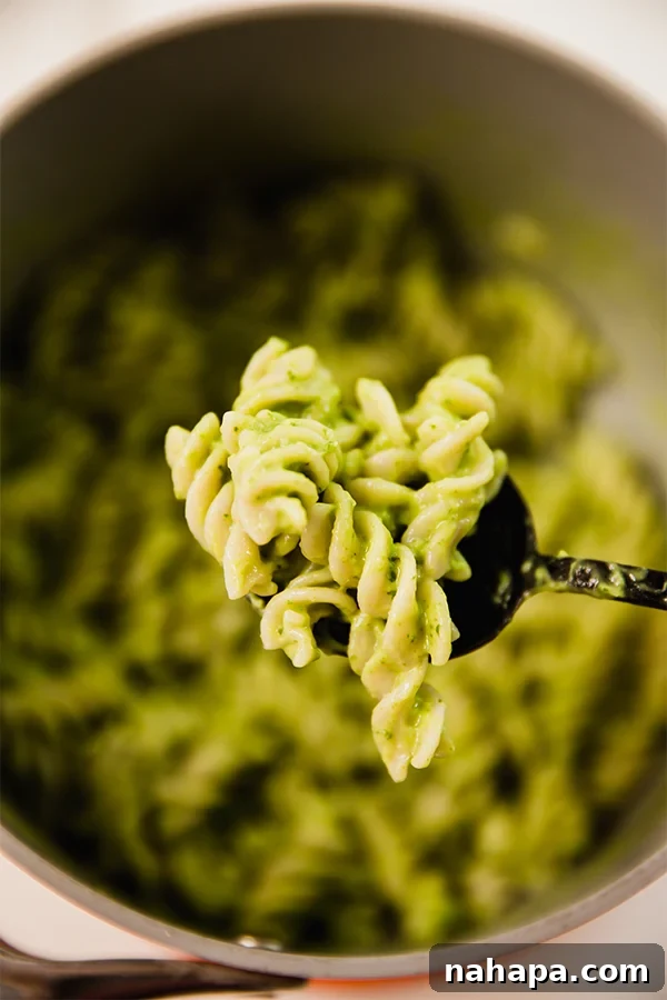 A serving of avocado pesto pasta on a spoon, showing its creamy texture.