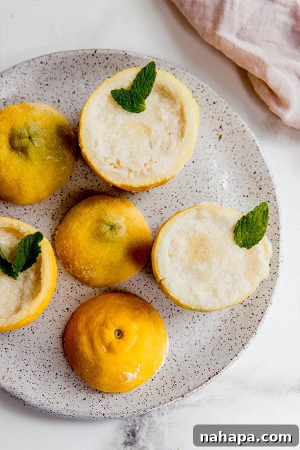 A beautifully presented plate of frozen lemon sorbet cups, garnished with mint leaves, ready to be enjoyed.