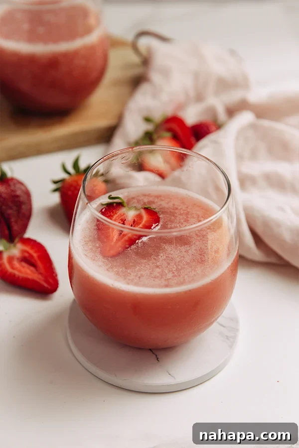 A cup of homemade frose, garnished with fresh strawberries.