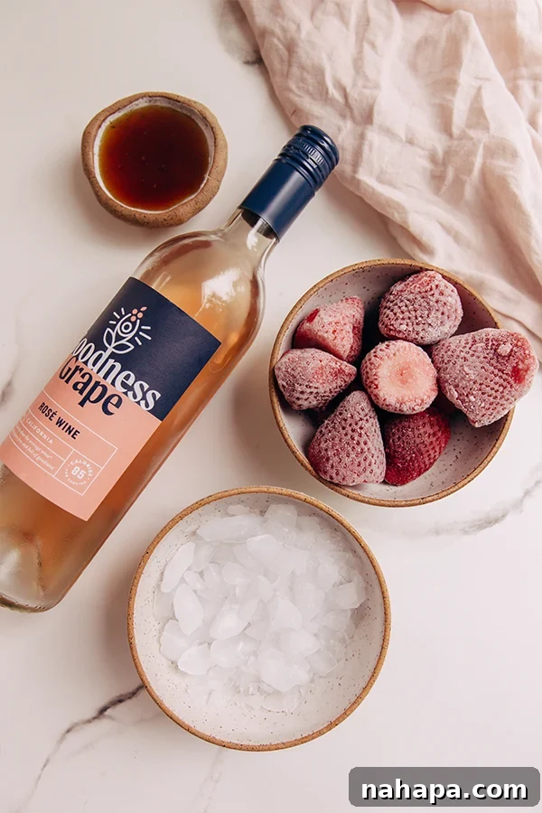 All the ingredients for frose laid out: rosé wine, frozen strawberries, honey, and ice.