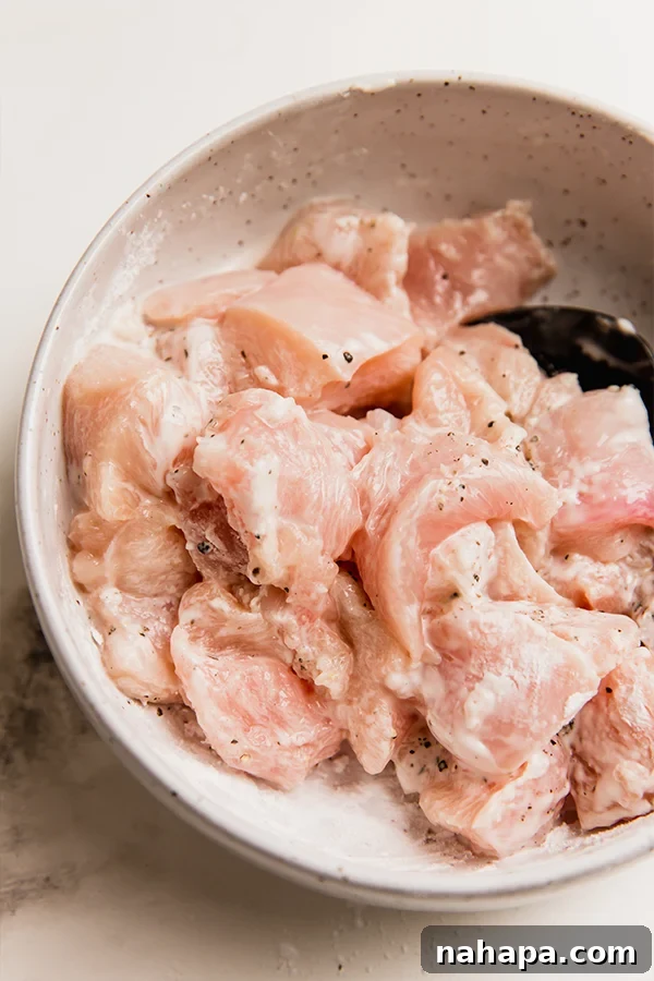 Chicken pieces tossed with arrowroot powder in a bowl, ready for cooking.