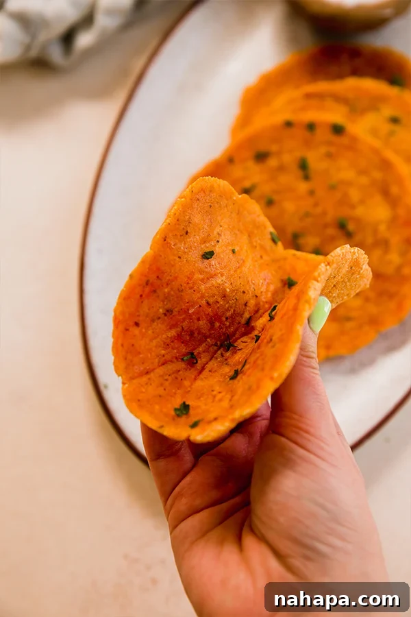 Golden Sweet Potato Flatbread 3 A single sweet potato flatbread gently held in a hand, showing its soft, flexible texture.