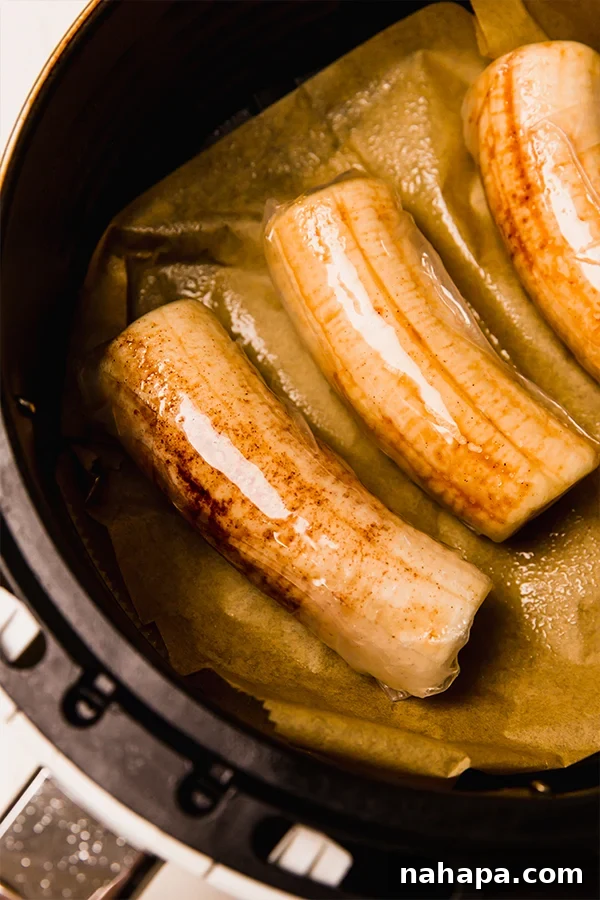 Several Gluten-Free Filipino Banana Lumpias cooking in an air fryer basket, turning golden brown and crispy.