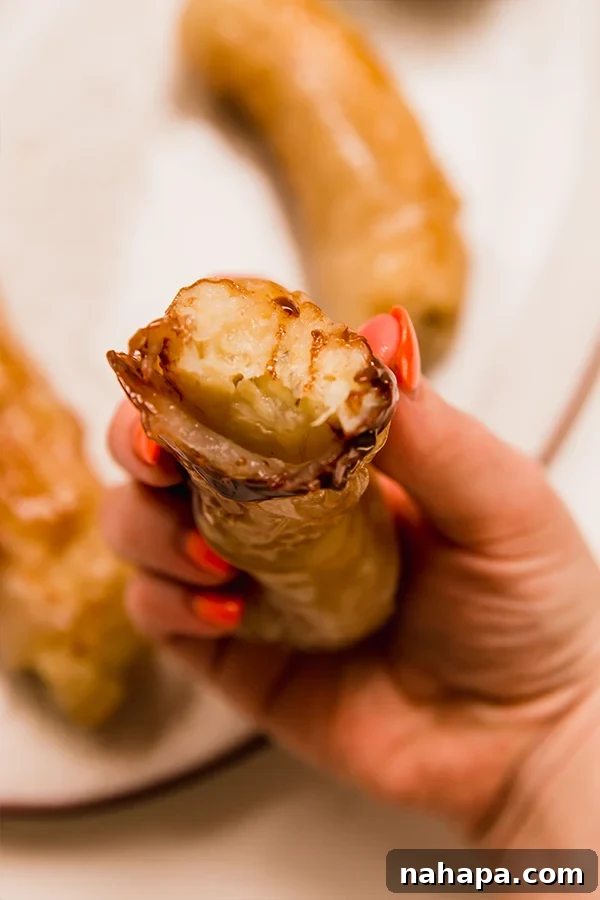 A hand presenting a perfectly fried Filipino Banana Lumpia, highlighting its crispy texture and golden-brown appearance.