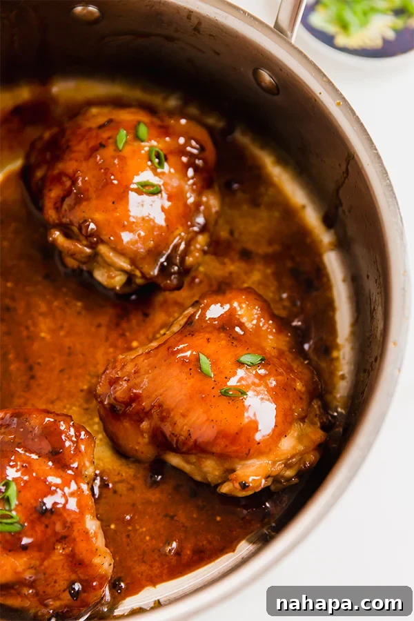 A pan cooking teriyaki chicken thighs, bubbling with sauce.