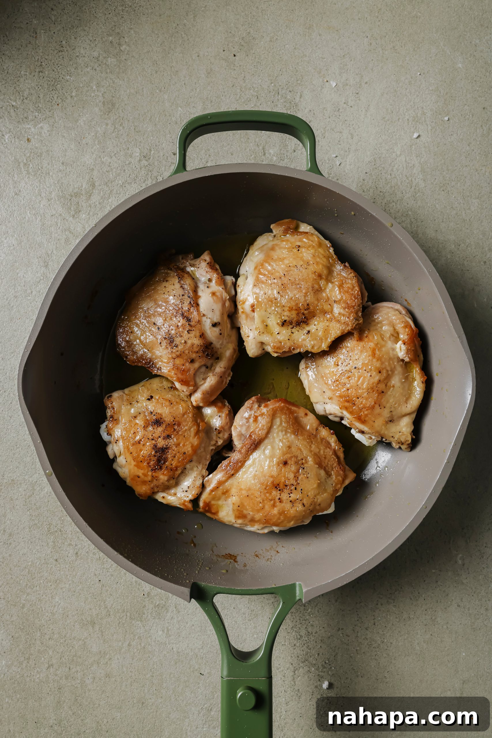 Hearty Slow Cooker Balsamic Chicken and Mixed Vegetables 5 Chicken thighs searing skin-side down in a hot skillet, achieving a golden-brown, crispy skin.