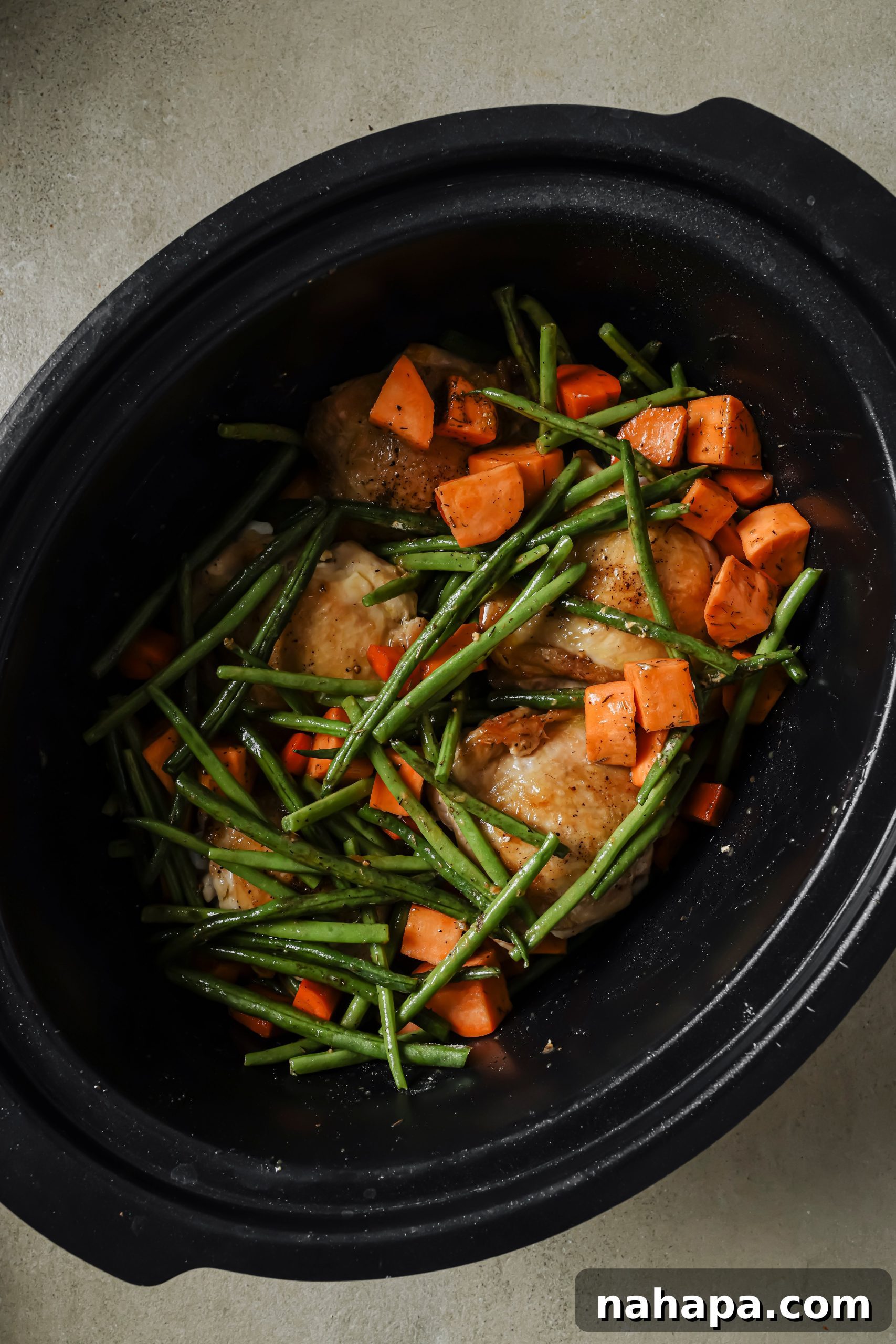 Hearty Slow Cooker Balsamic Chicken and Mixed Vegetables 6 Seared chicken thighs, chopped vegetables, and seasonings in the base of a slow cooker, ready for the liquids.