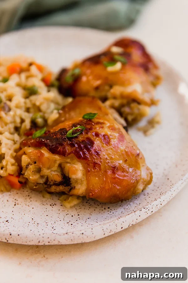 A plate with Asian-inspired chicken & rice, garnished with green onions and a squeeze of lime.