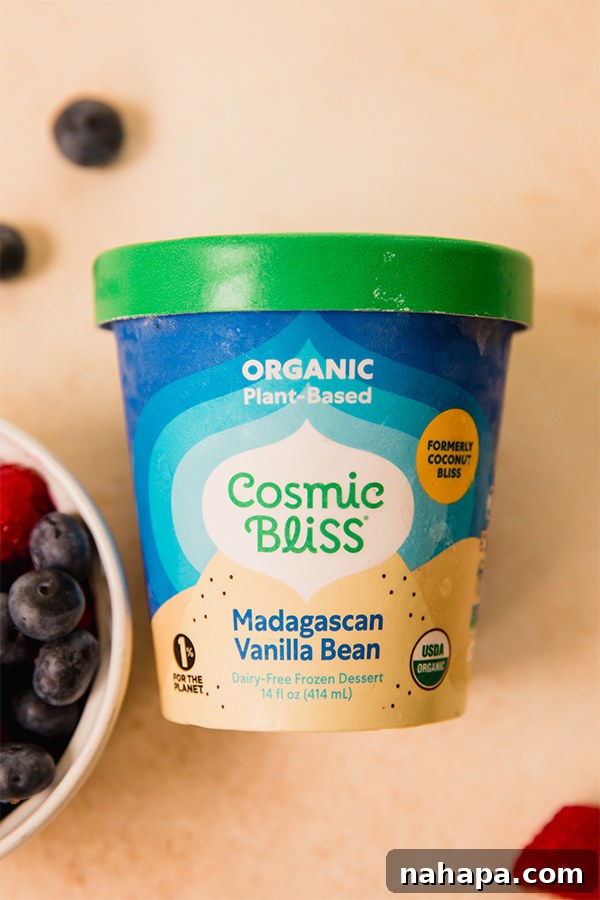 Ingredients for the no-bake ice cream cake laid out on a kitchen counter, showing dates, shredded coconut, berries, and Cosmic Bliss ice cream.