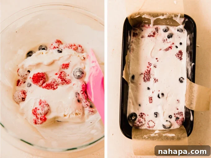 The ice cream mixture with berries being spread into the loaf pan over the crust, ready for freezing.