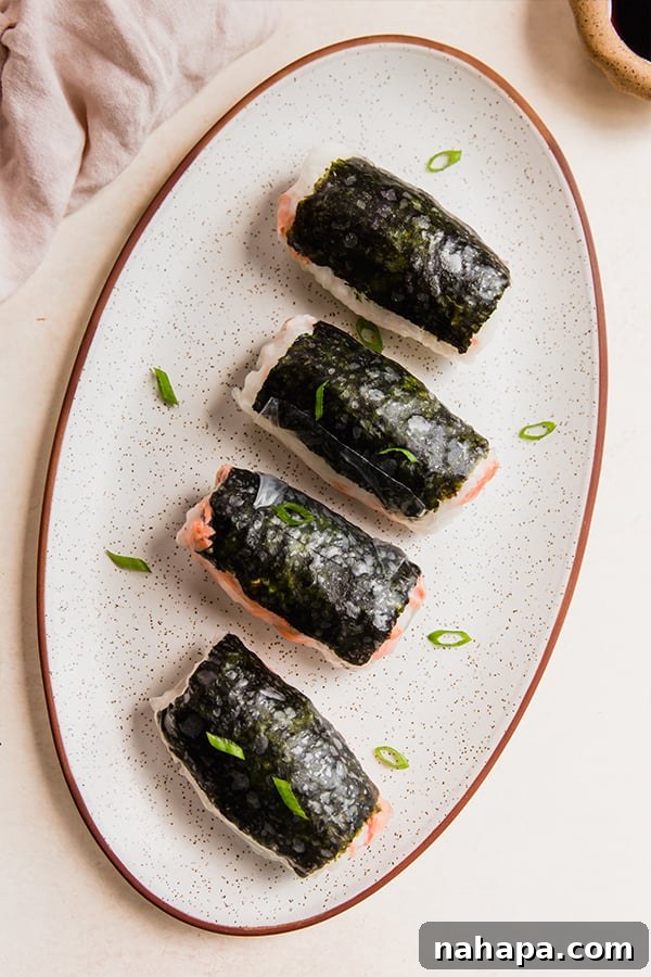A plate with sushi inspired salmon rice paper rolls on it.