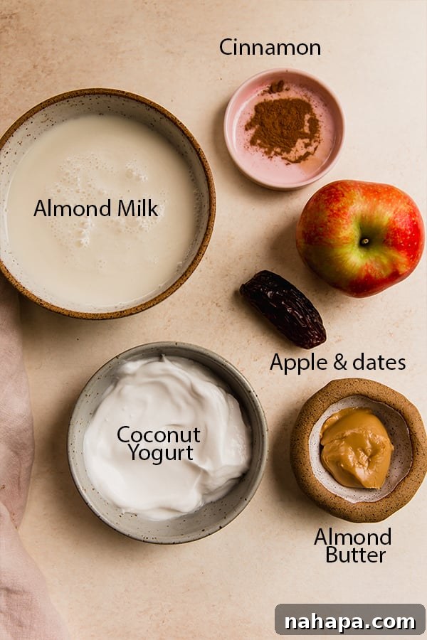 Orchard Fresh Sip 3 A flat lay photograph showcasing all the fresh ingredients required to make the apple smoothie, including whole apples, dates, cinnamon sticks, almond butter, and almond milk.