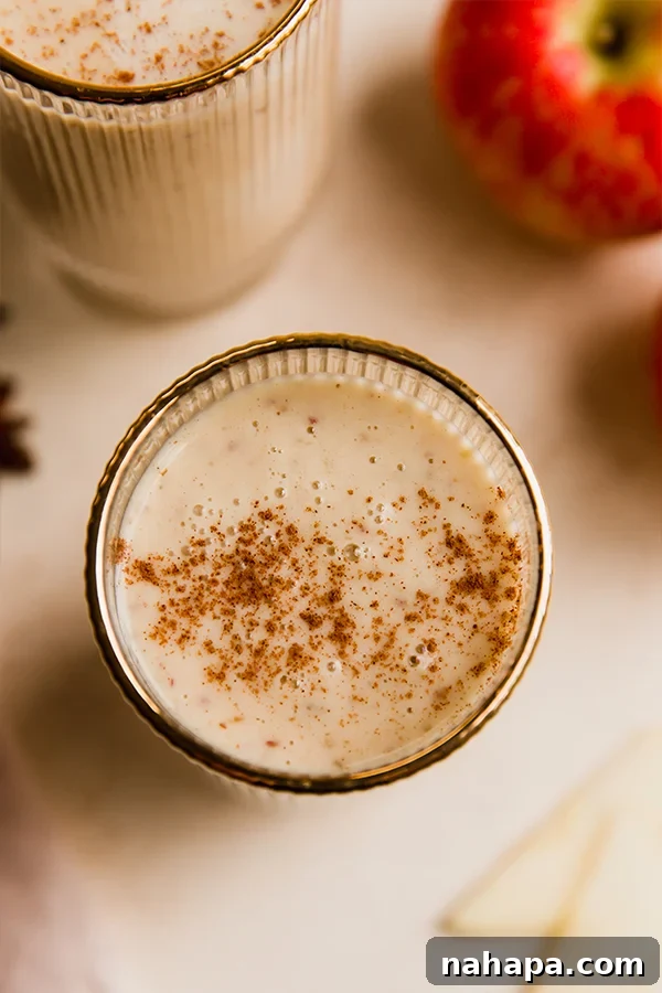 Orchard Fresh Sip 5 A single glass of the dairy-free apple smoothie, garnished with a sprinkle of cinnamon, sitting on a wooden surface.