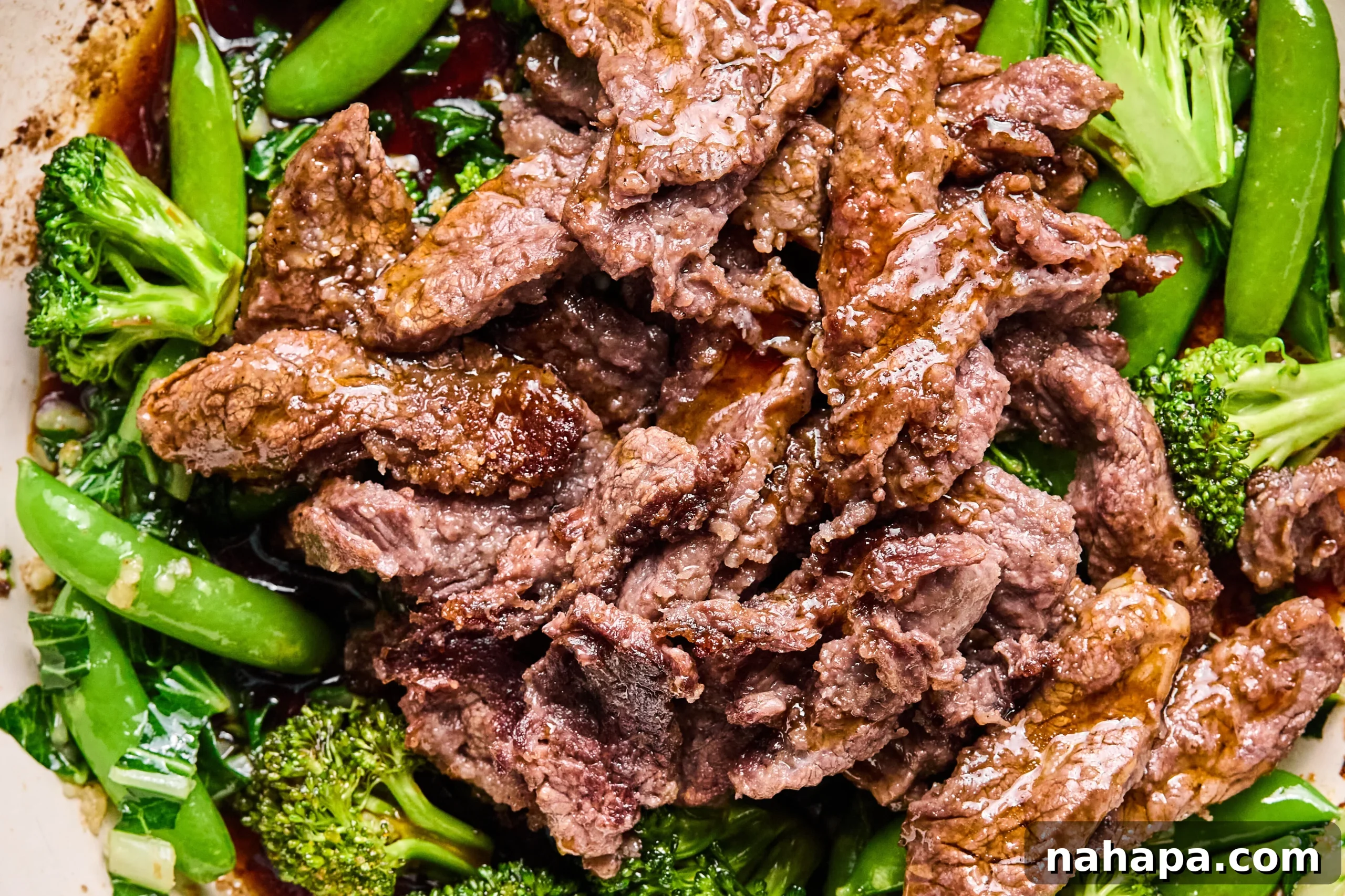 Cooked vegetables and beef being combined in the pan with the honey garlic sauce.