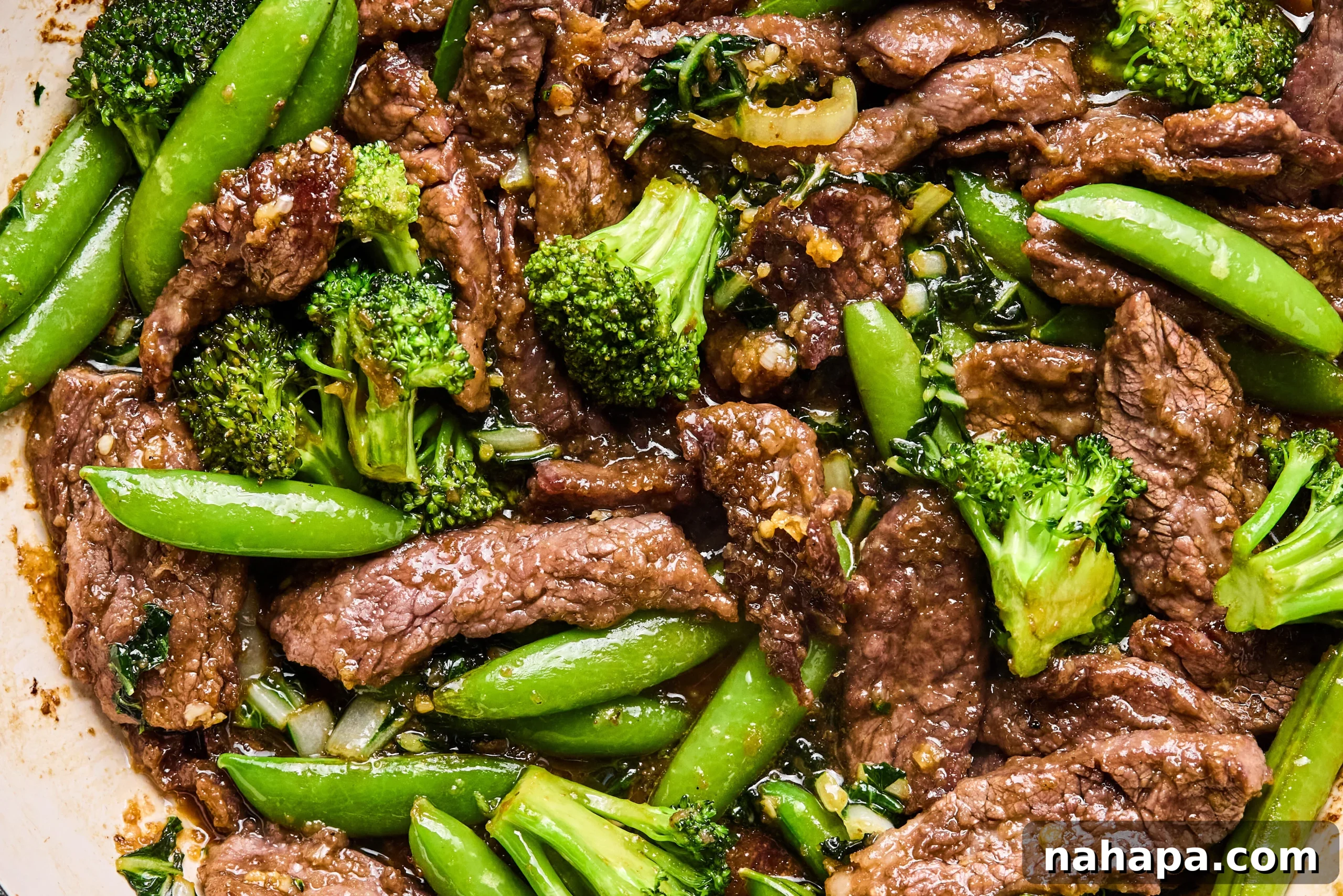 The final honey garlic beef stir fry in the pan, thoroughly coated in sauce and garnished with green onions before serving.