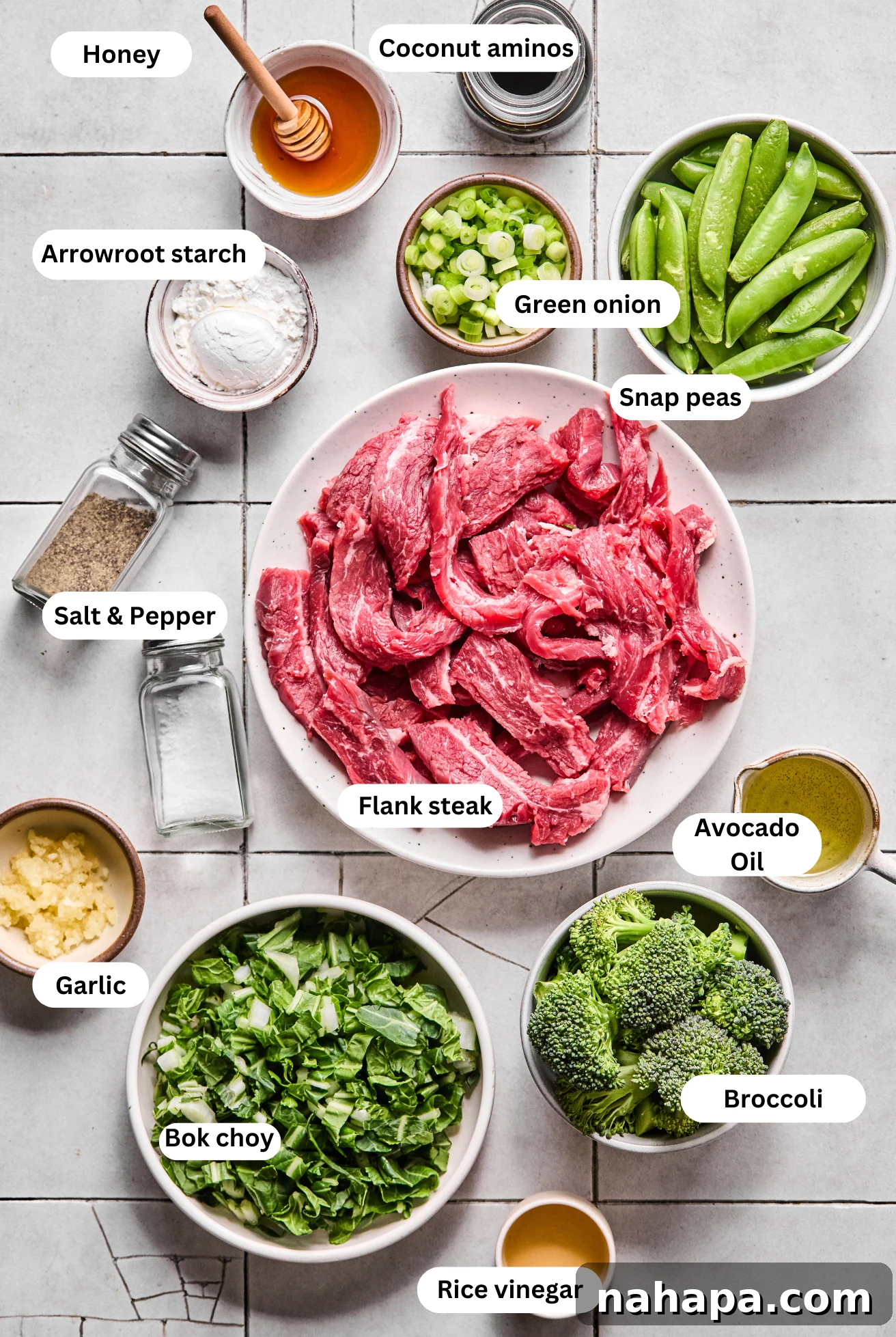 All of the fresh ingredients for honey garlic beef stir fry laid out before cooking, including flank steak, broccoli, snap peas, and sauce components.