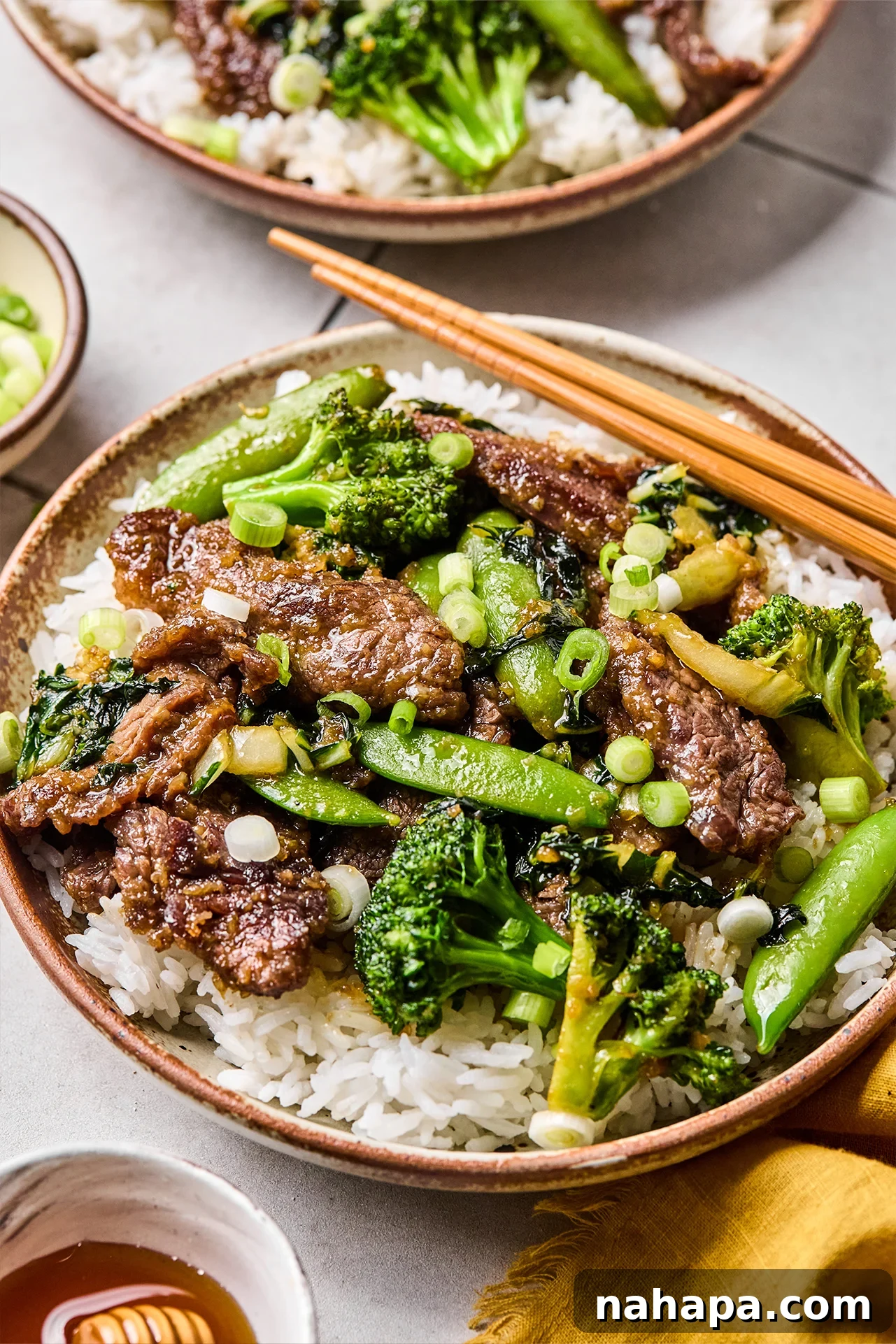 Honey garlic beef stir fry served over fluffy white rice, garnished with green onions.