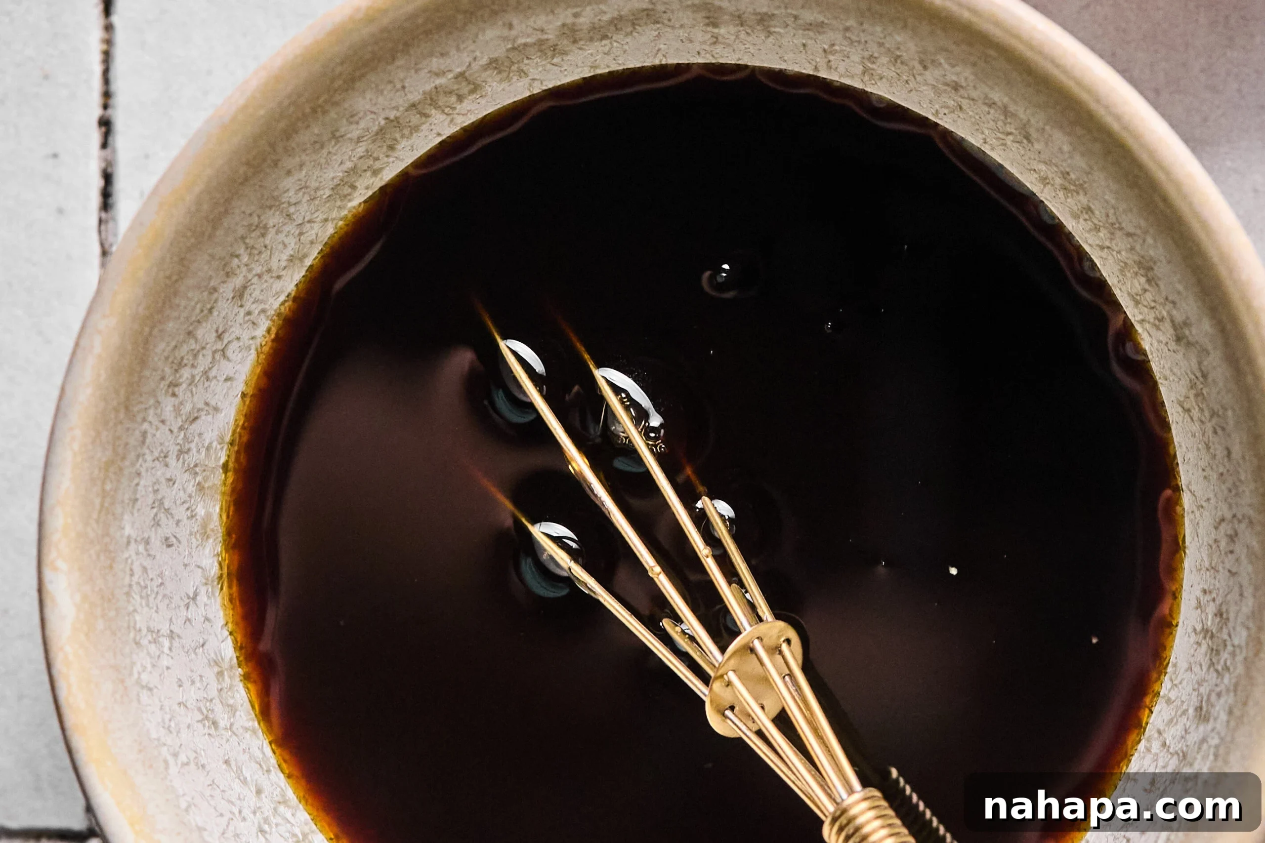 The stir fry sauce being made in a bowl, showing whisked coconut aminos, rice vinegar, and honey.
