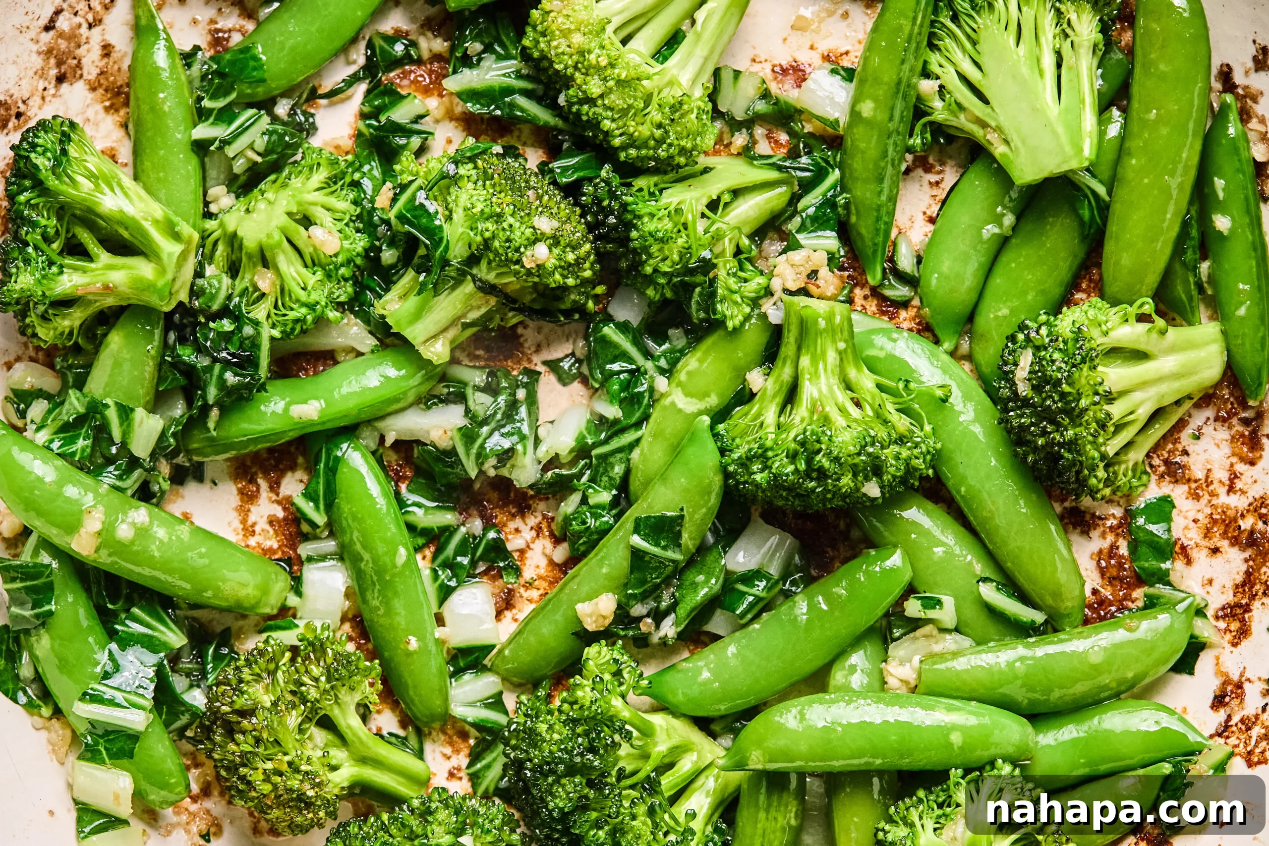 Broccoli, sugar snap peas, and bok choy sauting in a large pan with avocado oil.