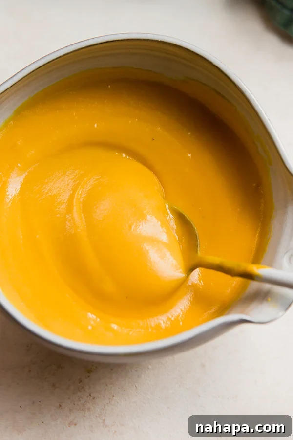 A bowl of dairy-free cheese sauce with a spoon.