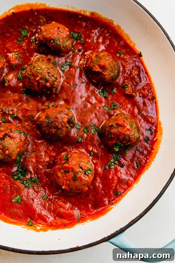 Rustic Italian Lamb Meatballs 5 Italian lamb meatballs in sauce in a pan.
