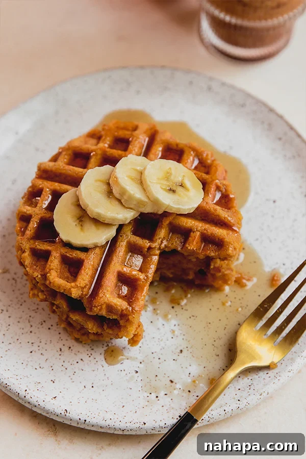Fluffy Paleo Pumpkin Waffles Vegan Gluten Free 5 A generous stack of warm pumpkin pancakes with a rich drizzle of maple syrup and fresh banana slices, appealing for a wholesome breakfast.