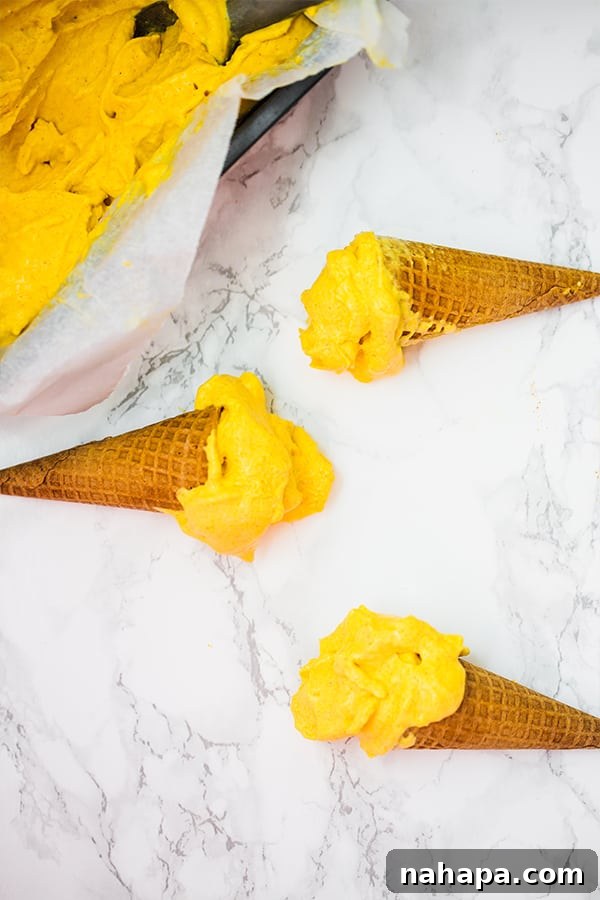 Three mango turmeric ice cream cones resting on a kitchen counter.