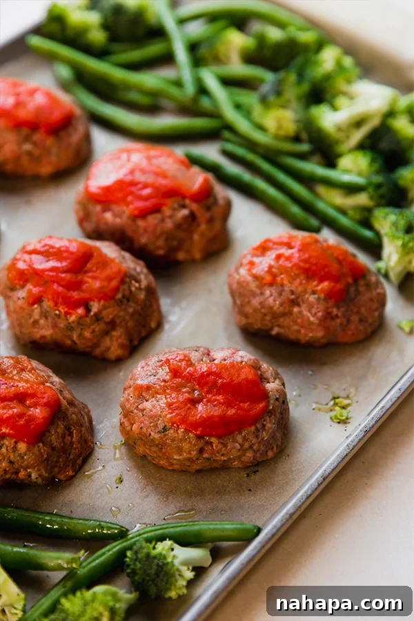 One-Pan Italian Mini Meatloaf & Roasted Vegetables (Gluten & Dairy-Free) 4 The Italian-Style Mini Meatloaf & Vegetable Sheet Pan with raw mini meatloaves topped with sauce and seasoned vegetables, ready for baking.